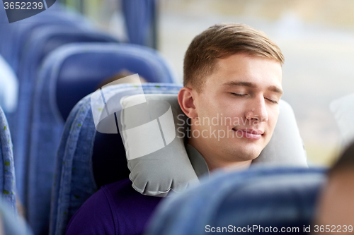 Image of happy young man sleeping in travel bus with pillow