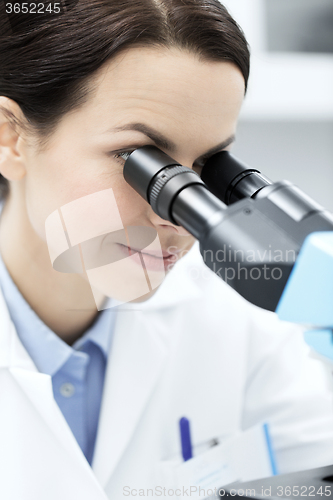 Image of close up of scientist looking to microscope in lab