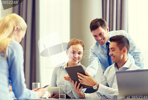 Image of smiling business people with tablet pc in office