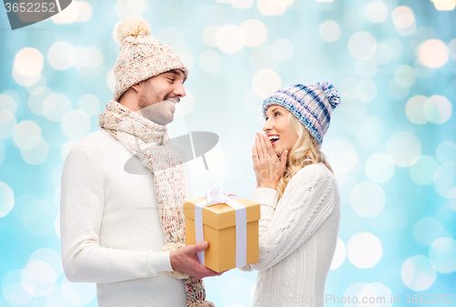 Image of smiling couple in winter clothes with gift box