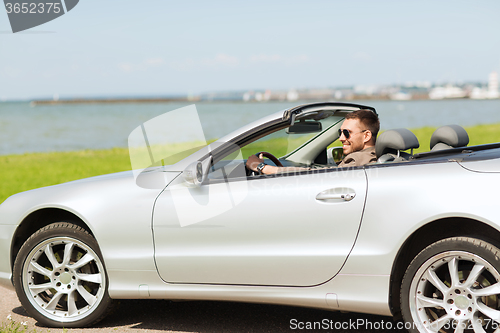 Image of happy man driving cabriolet car outdoors