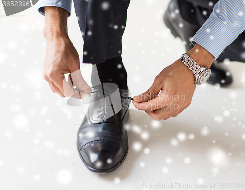 Image of close up of man leg and hands tying shoe laces