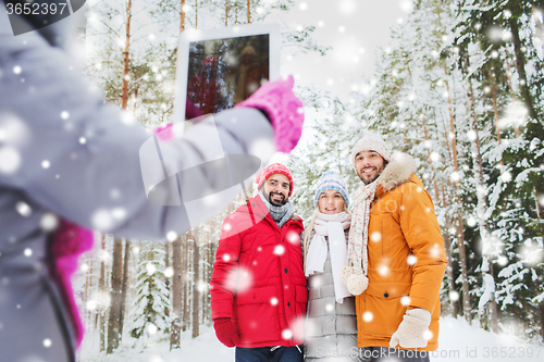 Image of smiling friends with tablet pc in winter forest