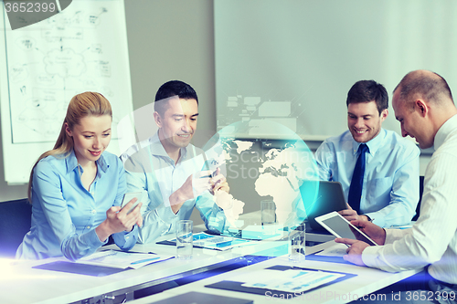 Image of smiling business people with gadgets in office