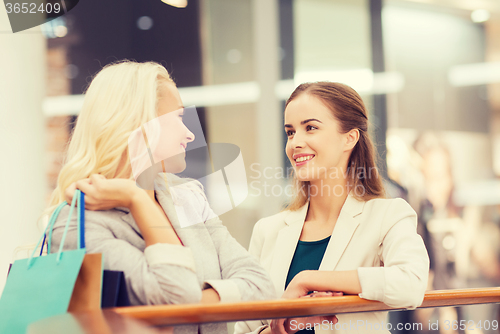 Image of happy young women with shopping bags in mall