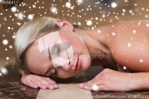 Image of young woman lying on hammam table in turkish bath