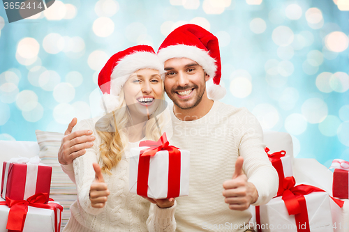 Image of happy couple with christmas gifts and thumbs up