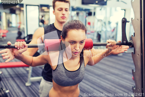 Image of man and woman with barbell flexing muscles in gym