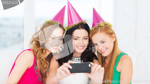 Image of three smiling women in hats having fun with camera
