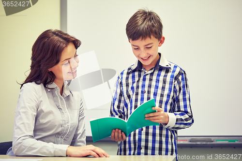 Image of school boy with notebook and teacher in classroom