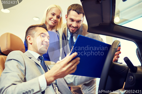 Image of happy couple with car dealer in auto show or salon