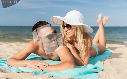 Image of happy couple in swimwear lying on summer beach