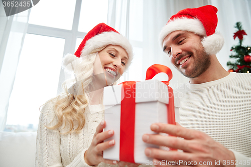 Image of happy couple at home with christmas gift box