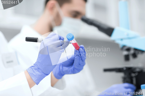 Image of close up of scientists hands with test tube in lab