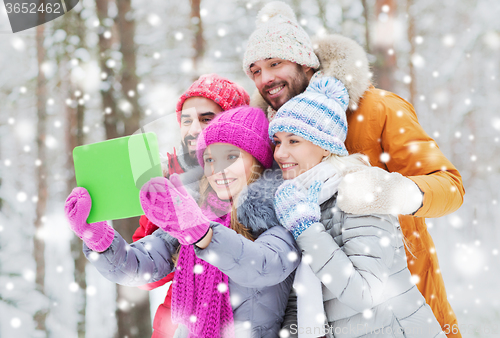 Image of smiling friends with tablet pc in winter forest