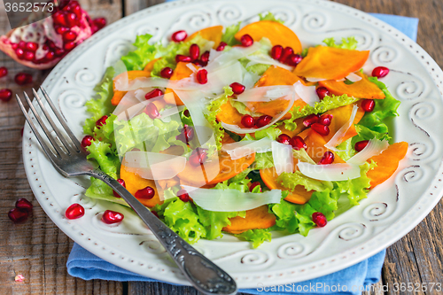 Image of Salad with persimmon and pomegranate seeds close-up.