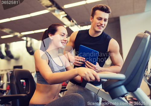 Image of happy woman with trainer on exercise bike in gym