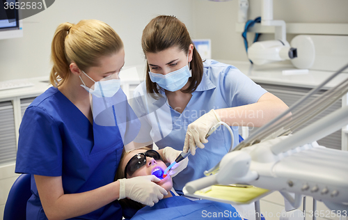 Image of female dentists treating patient girl teeth