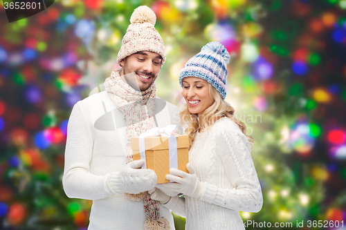 Image of smiling couple in winter clothes with gift box