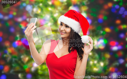 Image of woman in santa hat taking selfie by smartphone