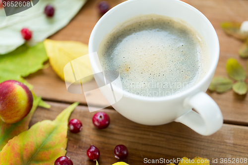 Image of close up of coffee cup on table with autumn leaves