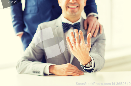 Image of close up of male gay couple with wedding rings on