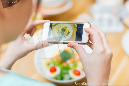 Image of woman with smartphone taking picture of food