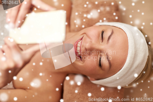 Image of close up of smiling woman with smartphone in spa