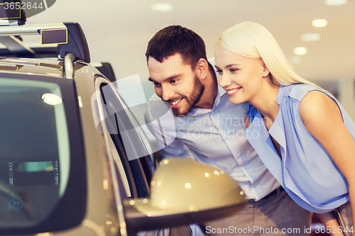 Image of happy couple buying car in auto show or salon