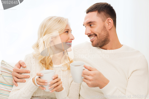 Image of happy couple with cups drinking tea at home