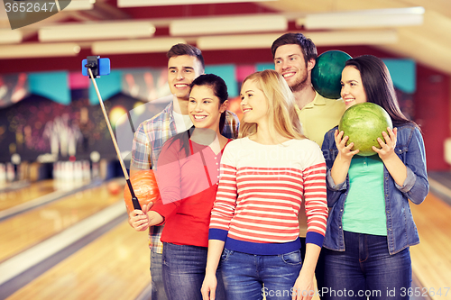 Image of happy friends taking selfie in bowling club