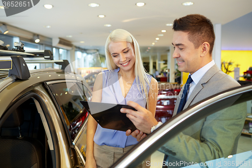 Image of happy woman with car dealer in auto show or salon