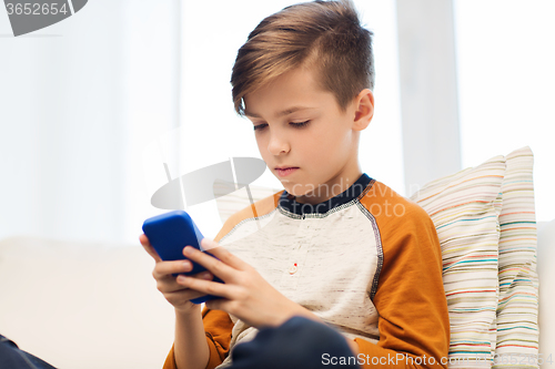 Image of boy with smartphone texting or playing at home