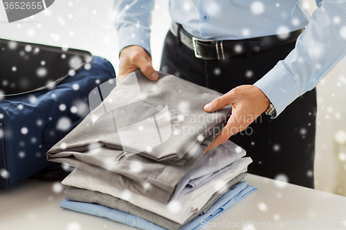 Image of businessman packing clothes into travel bag