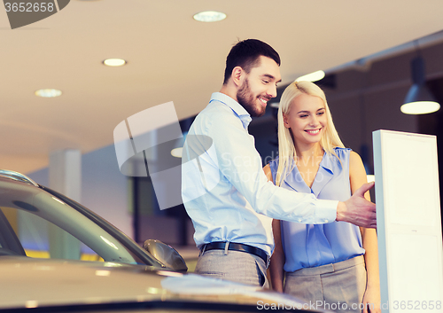 Image of happy couple buying car in auto show or salon