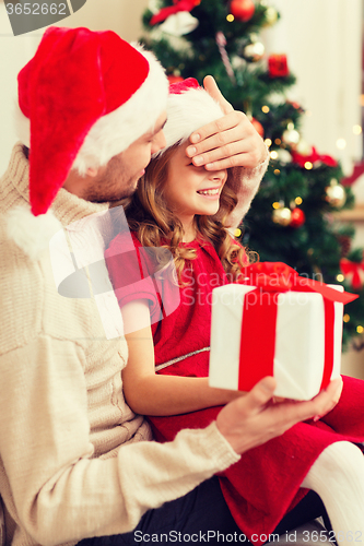 Image of smiling father surprises daughter with gift box