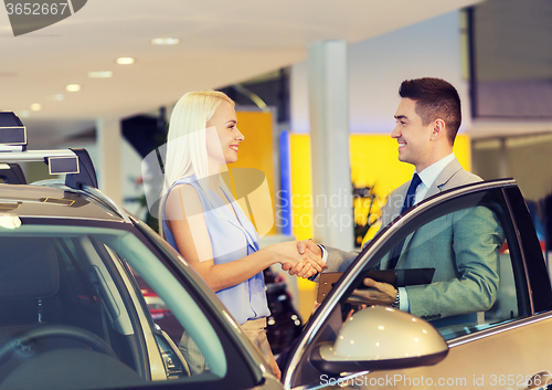 Image of happy woman with car dealer in auto show or salon