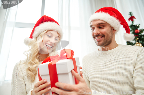 Image of happy couple at home with christmas gift box