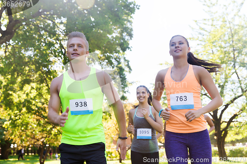 Image of happy young sportsmen racing wit badge numbers