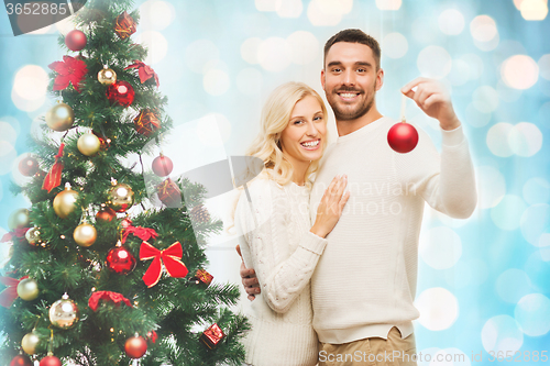 Image of happy couple decorating christmas tree at home