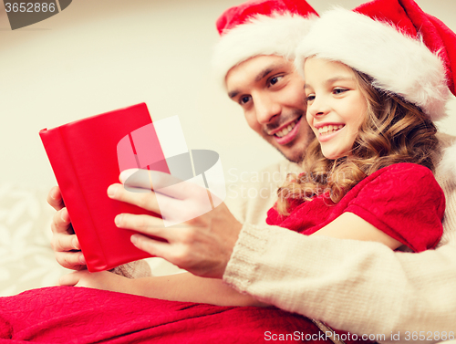 Image of smiling father and daughter reading book