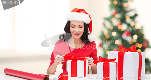 Image of woman in santa helper hat with many gift boxes