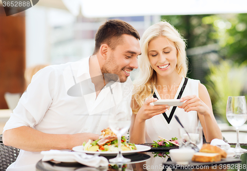 Image of happy couple with smatphone photographing food