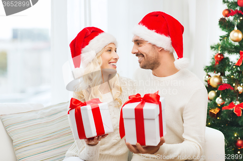 Image of happy couple at home exchanging christmas gifts