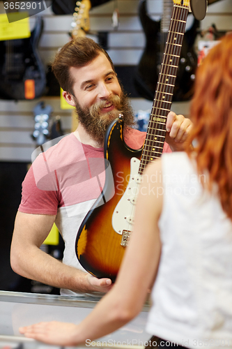 Image of assistant showing customer guitar at music store