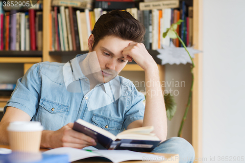 Image of male student reading book in library