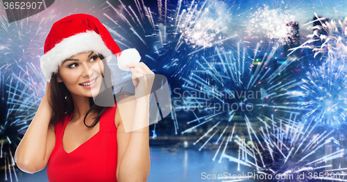 Image of woman in santa hat and red dress over firework