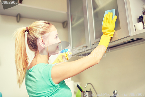 Image of happy woman cleaning cabinet at home kitchen