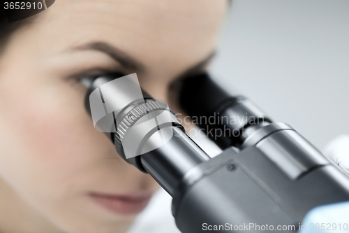 Image of close up of scientist looking to microscope in lab