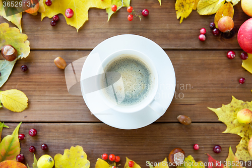 Image of close up of coffee cup on table with autumn leaves